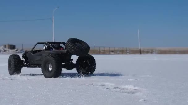 Радиоуправляемая машина: маленькая черная коляска, мчащаяся на бешеной скорости по свежему снегу . — стоковое видео