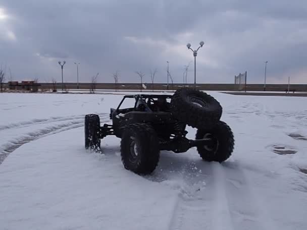 Радиоуправляемая машина: маленькая черная коляска, мчащаяся на бешеной скорости по свежему снегу . — стоковое видео