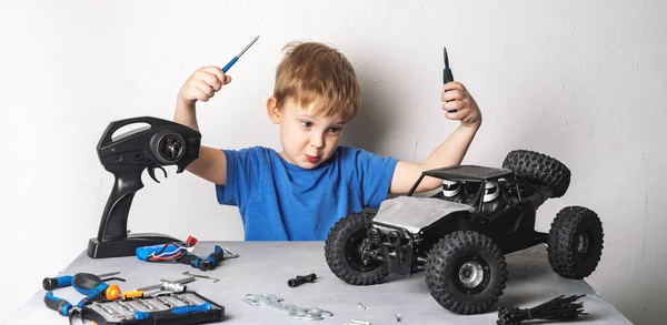 Modelos controlados por rádio: Um menino em uma camiseta azul está reparando seu buggy RC. — Fotografia de Stock