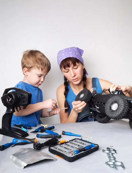 Mujeres en el trabajo de los hombres: Mamá ayuda a su hijo con la fijación de un modelo de buggy controlado por radio . — Foto de Stock