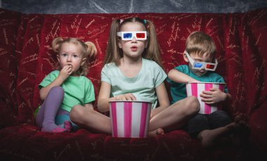 Çocuk sinema: çocuk kırmızı kanepede oturup bir 3d film seyretmek.