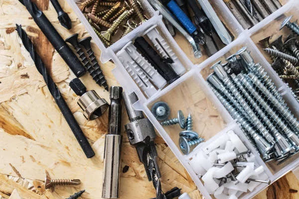 Vidalar, dübeller, matkaplar, arka planda parçaları Osb ile plastik şeffaf Organizatör.