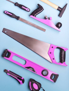 Yaratıcı provokasyon: pembe el aletleri inşaat ve onarım mavi bir arka plan üzerinde bir dizi.