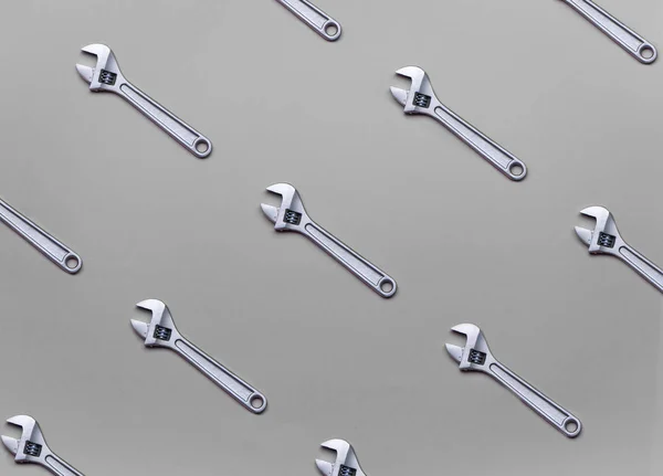 The pattern of adjustable wrenches on a gray background. — Stock Photo, Image