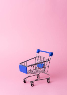 Bayan alışveriş: pembe bir arka planda bir süpermarketten boş bir minyatür arabası.