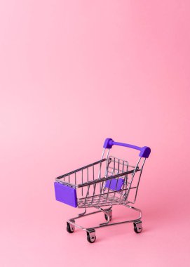 Kadın alışverişi: pembe arka planda süpermarketten alınmış boş bir minyatür mor tramvay..
