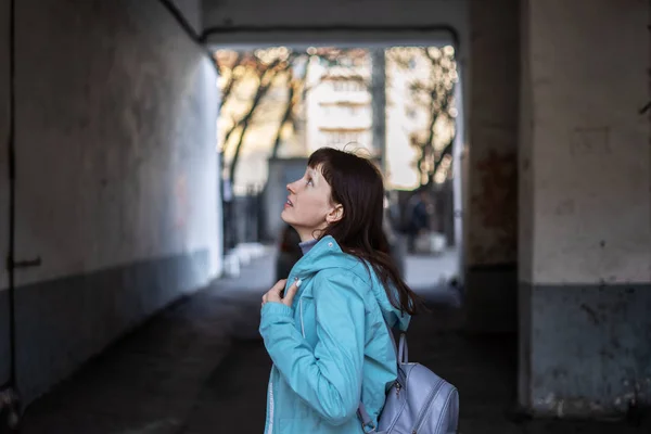 汚れた旧市街の壁の中で青いジャケットを着た陽気な女の子. — ストック写真