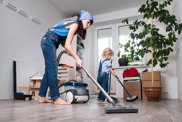Mom and daughter in blue denim overalls cleaned at home and vacuumed. — Stock Photo, Image