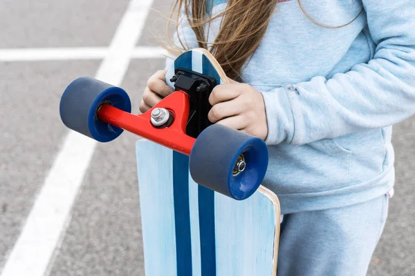 Een meisje in een blauwe jas met een groot Longboard. — Stockfoto