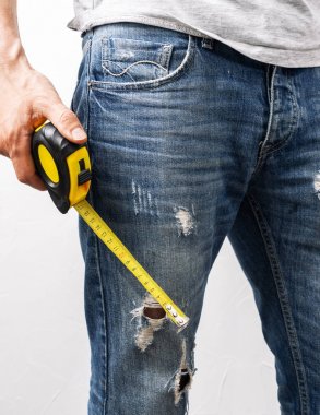 Doğrama: Bir adam elinde sarı bir ölçüm bandı tutar.