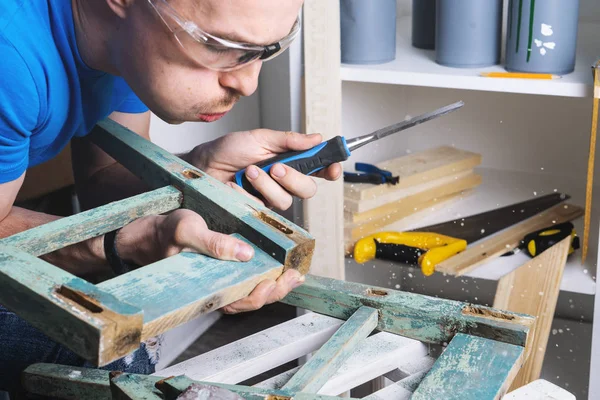 Joinery: furniture master restores the old, dilapidated stool. Closeup of a mans hand.