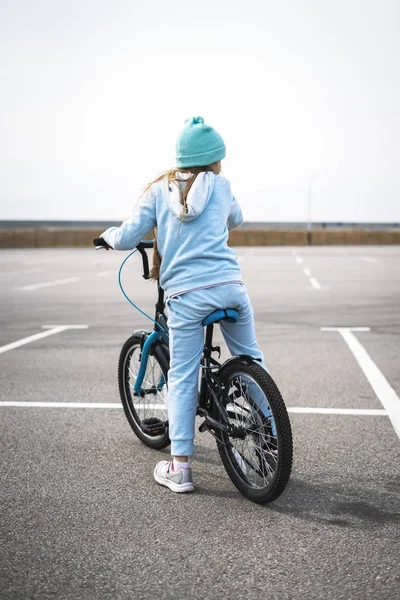 Een meisje in een hoed en een blauwe trui op een fiets gestopt en kijkt rond. — Stockfoto