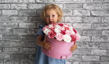 Bir çocuktan bir hediye: hasta yuvarlak pembe kutuda büyük bir buket gül ile küçük bir kız.