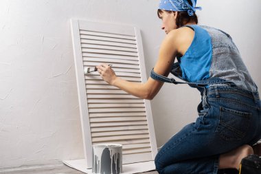 Ev onarım: kız mavi tişört ve kot pantolon beyaz boya ile kabine cephe boyalar. Gerçek kişi.