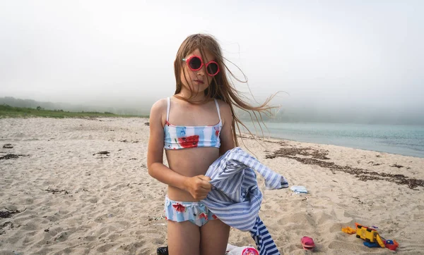 Девочка в солнечных очках на туманном берегу моря . — стоковое фото