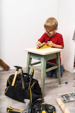 Küçük bir çocuk bir planör ile eski bir tabure planlıyor.
