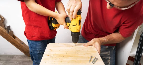 Baba oğluna matkapla çalışmayı öğretiyor..