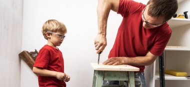 Baba küçük oğluna tornavidayla vidaları nasıl sıkacaklarını gösteriyor..