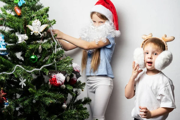 Chłopiec i dziewczynka w czapce Santa udekorować choinkę. Portret rodziny. — Zdjęcie stockowe