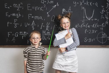 Neşeli erkek ve kız öğrenciler tahta ve stetrads duruyor. Birçok formüller tahtaya yazılır.