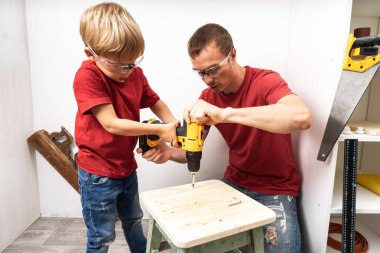 Baba oğluna matkapla çalışmayı öğretiyor..