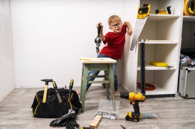 Bir çocuk el matkabında çalışıyor ve mobilyaları tamir ediyor.