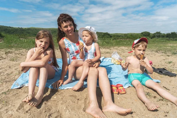 Мама и дети сидят на песке у моря . — стоковое фото