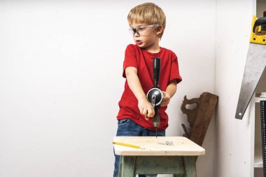 Bir çocuk el matkabında çalışıyor ve mobilyaları tamir ediyor.