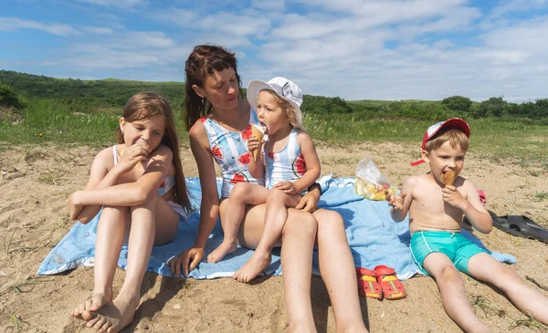 お母さんと子供たちは海辺の砂の上に座っている. — ストック写真