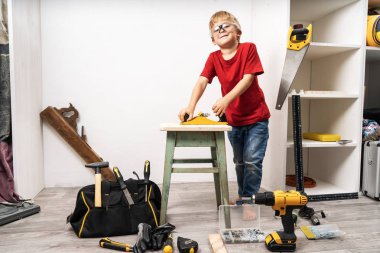 Küçük bir çocuk bir planör ile eski bir tabure planlıyor.