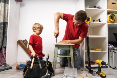 Baba küçük oğluna tornavidayla vidaları nasıl sıkacaklarını gösteriyor..
