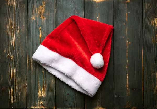 Red Santa Claus pălărie pe un fundal verde din lemn . — Fotografie, imagine de stoc