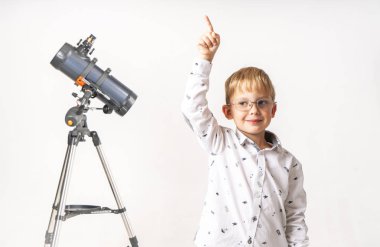 Küçük bir çocuk teleskopun başında duruyor ve parmağını yukarı kaldırıyor..