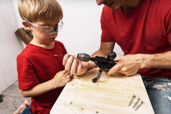 Pai ensina filho a trabalhar com uma broca de mão. — Fotografia de Stock
