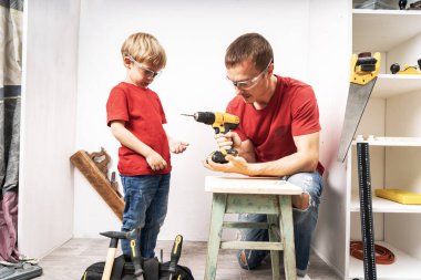 Baba oğluna matkapla çalışmayı öğretiyor..