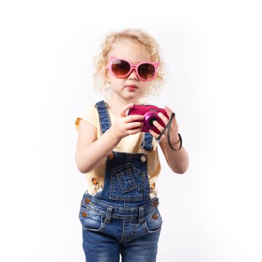 Pembe güneş gözlüklü küçük kız ve pembe bebek kamerası..