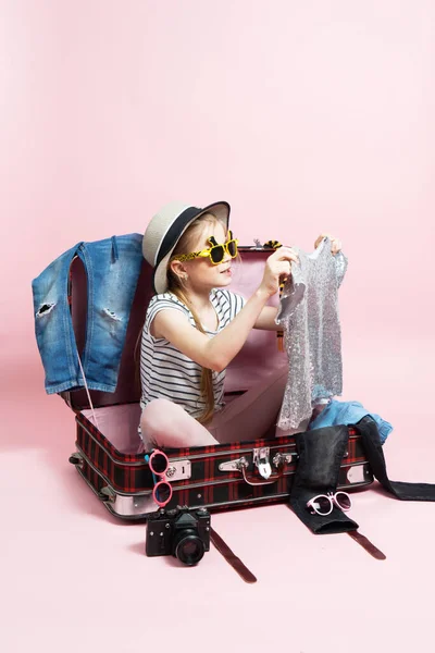 Viajes: Una colegiala se prepara para un viaje y recoge la ropa en una maleta grande. —  Fotos de Stock
