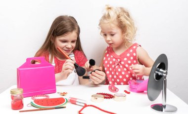 Bebek kozmetik ürünleri: iki küçük kız yüz estetiği kullanıyor.