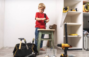 Bir çocuk el matkabında çalışıyor ve mobilyaları tamir ediyor.