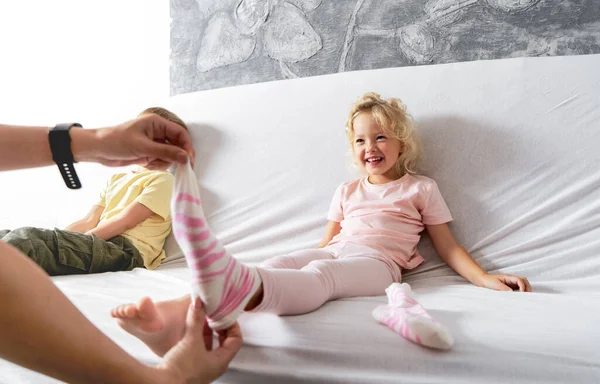 Anya leveszi a kislányai zokniját és csiklandozza a lábát egy kicsit. A lány nevet.. — Stock Fotó