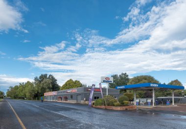 HIMEVILLE, SOUTH AFRICA - MARCH 25, 2018: A street scene with gas station and automotive businesses in Himeville in the Kwazulu-Natal Province clipart