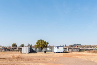 PRETORIA, SOUTH AFRICA, JULY 31, 2018: The Woodlands Village clinic at the Plastic View informal township bordering the Dutch Reformed Church Moreletta Park in Pretoria. Shacks are visible clipart