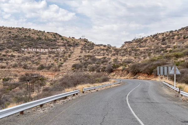 Kuzey Cape Eyaleti 'ndeki Vanderkloof kasabasına giden yol. Kasabanın adı tepenin yamacında görünür.