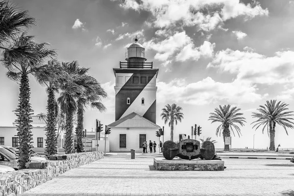 CAPE TOWN, SOUTH AFRICA, AUGUST 17, 2018: The Green Point Lighthouse at Mouille Point in Cape Town in the Western Cape Province. An historic ships anchor and people are visible. Monochrome