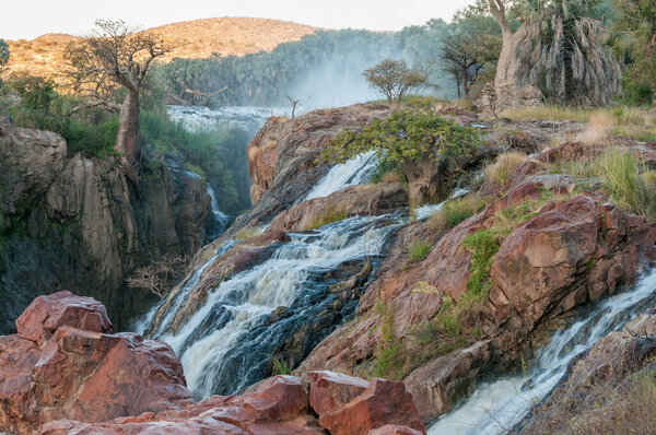 Part of the Epupa waterfalls in the Kunene River at sunset. Baobab trees are visible