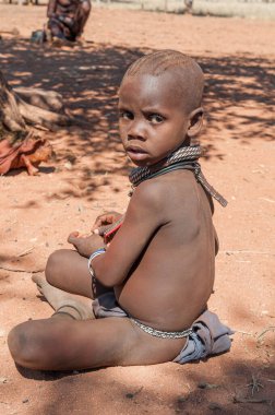 EPUPA, NAMIBIA - 27 Mayıs 2011: Epupa yakınlarındaki Himba köyünde fotoğrafçılara poz veren genç bir Himba çocuğu