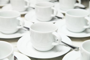 Beyaz seramik kupa ve tabloda çay kaşığı fincan tabağı birçok satır