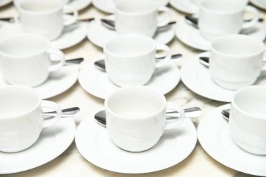 Beyaz seramik kupa ve tabloda çay kaşığı fincan tabağı birçok satır