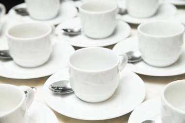 Beyaz seramik kupa ve tabloda çay kaşığı fincan tabağı birçok satır