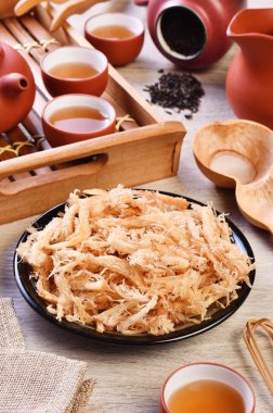 Ahşap masada çay ile rendelenmiş kurutulmuş kalamar                                                                                                                               